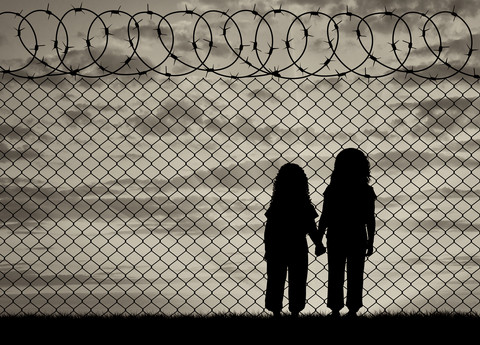 barn som ser gjennom piggjerde